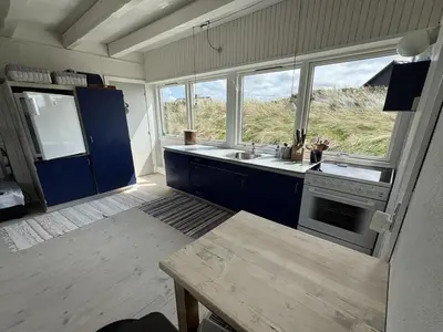 a kitchen with blue cabinets and a sink and windows at Holiday Home Wighlek - 800m from the sea by Interhome in Snedsted
