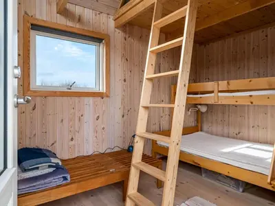 a bunk bed in a wooden cabin with a window at Holiday Home Wighlek - 800m from the sea by Interhome in Snedsted