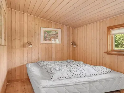 a bed in a room with a wooden wall at Holiday Home Rieke - 2km from the sea by Interhome in Blokhus