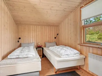 two beds in a room with wooden walls at Holiday Home Rieke - 2km from the sea by Interhome in Blokhus