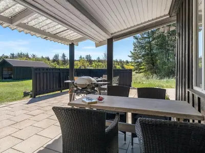 a patio with a wooden table and chairs at Holiday Home Rieke - 2km from the sea by Interhome in Blokhus