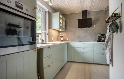 a kitchen with white cabinets and a tv on the wall at Nice Home In Roslev With House Sea View in Roslev