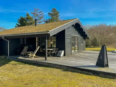 a small cabin with a wooden deck at Traditional Summer House Near Blokhus Beach in Blokhus