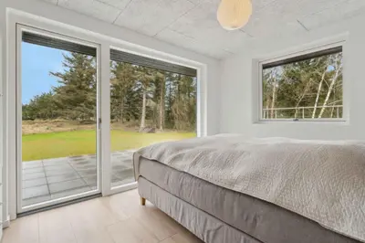 a bedroom with a bed and sliding glass doors at Holiday Home In 1St Row By The Limfjord in Thyholm