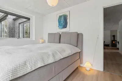 a white bedroom with a large bed and a window at Holiday Home In 1St Row By The Limfjord in Thyholm