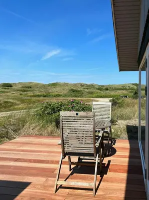 a patio with a table and chairs on a deck at Cosy, Traditional Summer House Close To The North Sea in Fjerritslev