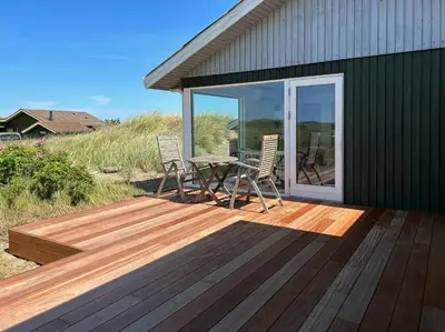 a patio with a table and chairs on a deck at Cosy, Traditional Summer House Close To The North Sea in Fjerritslev