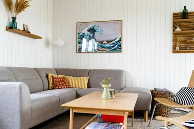a living room with a couch and a painting of a wave at Cosy, Traditional Summer House Close To The North Sea in Fjerritslev