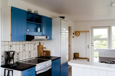 a kitchen with blue cabinets and a black counter top at Cosy, Traditional Summer House Close To The North Sea in Fjerritslev