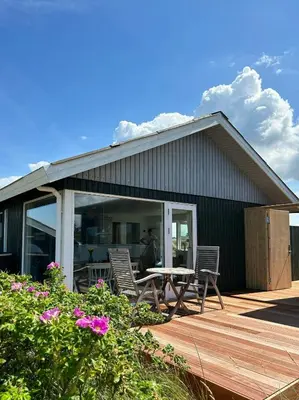 a house with chairs and a table on a deck at Cosy, Traditional Summer House Close To The North Sea in Fjerritslev