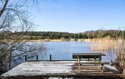 a picnic table sitting on a dock in front of a lake at Lovely Home In Nibe With Lake View in Nibe