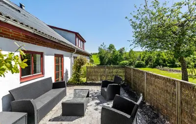 a patio with chairs and a table and a fence at Lovely Home In Nibe With Lake View in Nibe