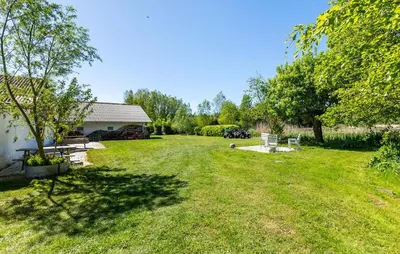 a yard with chairs and a building and trees at Lovely Home In Nibe With Lake View in Nibe