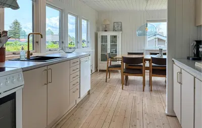 a kitchen with white cabinets and a dining room with a table at 3 Bedroom Stunning Home In Øster Assels in Øster Assels
