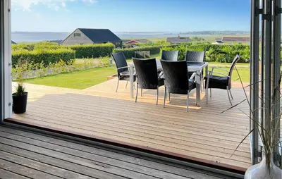 a wooden deck with a table and chairs on it at 3 Bedroom Stunning Home In Øster Assels in Øster Assels