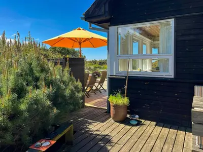 a patio with an umbrella and a table and chairs at Architect-Designed Holiday Home By Saltum Beach in Saltum