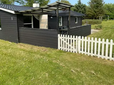 a small black house with a white fence at Family House By Frederik Vii Canal In Løgstør in Løgstør
