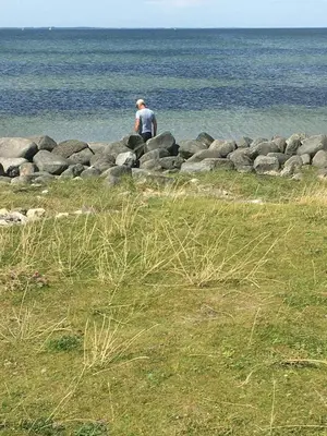 a man standing on some rocks near the water at Family House By Frederik Vii Canal In Løgstør in Løgstør