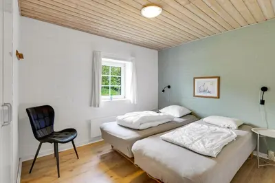 two beds in a room with a chair and a window at Large Pool House For 24 People, With Almost Everything In Activities, 300 Meters From The Fjord in Vinderup