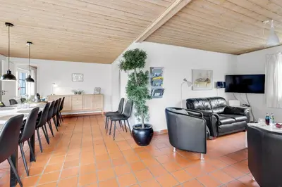 a living room with black leather chairs and a table at Large Pool House For 24 People, With Almost Everything In Activities, 300 Meters From The Fjord in Vinderup