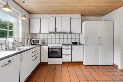 a kitchen with white appliances and white cabinets at Large Pool House For 24 People, With Almost Everything In Activities, 300 Meters From The Fjord in Vinderup