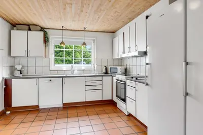 a kitchen with white cabinets and a window at Large Pool House For 24 People, With Almost Everything In Activities, 300 Meters From The Fjord in Vinderup