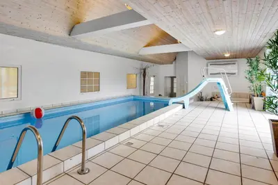 an indoor swimming pool with a slide in a building at Large Pool House For 24 People, With Almost Everything In Activities, 300 Meters From The Fjord in Vinderup