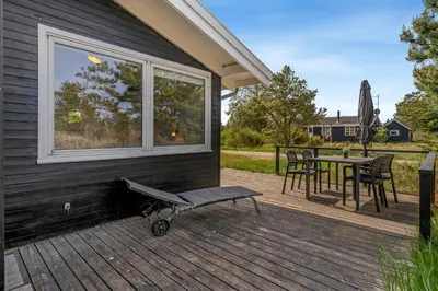a deck with a table and chairs and a window at Well-Maintained Holiday Home With Outdoor Shower And 5-Person Outdoor Hot Tub, Close To The North Sea In Klitmøller in Klitmøller