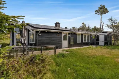 a house with a fence in front of a yard at Well-Maintained Holiday Home With Outdoor Shower And 5-Person Outdoor Hot Tub, Close To The North Sea In Klitmøller in Klitmøller