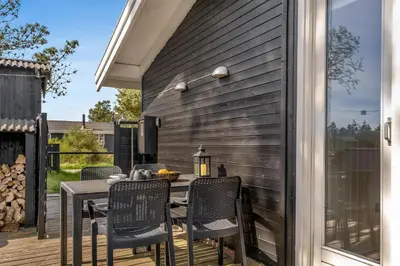 a patio with a table and chairs on a deck at Well-Maintained Holiday Home With Outdoor Shower And 5-Person Outdoor Hot Tub, Close To The North Sea In Klitmøller in Klitmøller