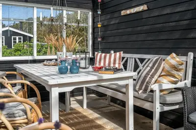 a white table and chairs on a patio at Beautifully Renovated Holiday Home With Covered Terrace And Wood-Burning Stove, Close To The North Sea In Thy in Sønder Vorupør