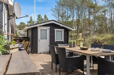 a backyard with a table and chairs and a shed at Beautifully Renovated Holiday Home With Covered Terrace And Wood-Burning Stove, Close To The North Sea In Thy in Sønder Vorupør