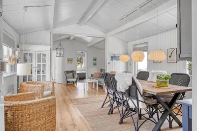 a dining room and living room with a table and chairs at Beautifully Renovated Holiday Home With Covered Terrace And Wood-Burning Stove, Close To The North Sea In Thy in Sønder Vorupør
