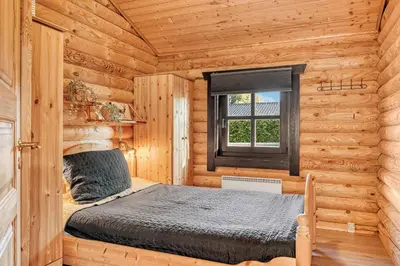 a bedroom with a bed in a log cabin at Well-Maintained Log House With Hot Tub, Sauna And Covered Terrace In Thy