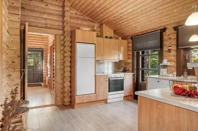 a kitchen with wooden cabinets and a white refrigerator at Well-Maintained Log House With Hot Tub, Sauna And Covered Terrace In Thy