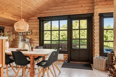 a dining room with a large wooden table and chairs at Well-Maintained Log House With Hot Tub, Sauna And Covered Terrace In Thy