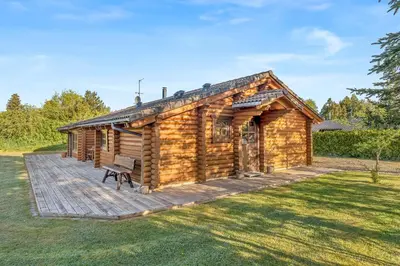 a log cabin with a bench on a deck at Well-Maintained Log House With Hot Tub, Sauna And Covered Terrace In Thy