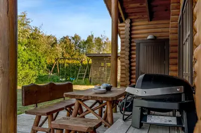 a grill and a picnic table on a porch of a cabin at Well-Maintained Log House With Hot Tub, Sauna And Covered Terrace In Thy