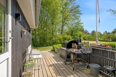 a wooden deck with a grill on the side of a house at Lovely Renovated Holiday Home With A Wilderness Bath And Fenced Grounds in Vesløs