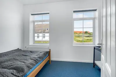 a bedroom with a bed and two windows at Renovated Holiday Home With Free Consumption, Close To The North Sea And The Center Of Hanstholm in Hanstholm