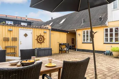 a wooden table with chairs and an umbrella on a patio at Charming Townhouse From 1877, Located In The Middle Of Løgstør Only 100 Meters From The Harbor in Løgstør