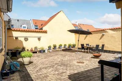 a patio with a table and an umbrella at Charming Townhouse From 1877, Located In The Middle Of Løgstør Only 100 Meters From The Harbor in Løgstør