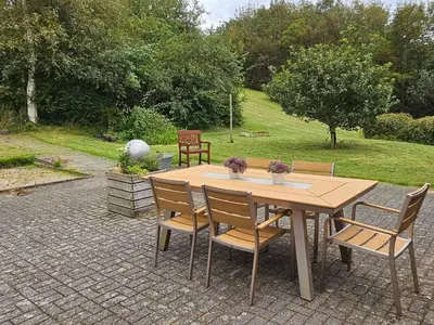 a wooden table and chairs on a brick patio at Cozy Danish Room for Solo Stays in Lemvig
