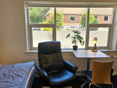 a room with a chair and a table and a window at Cozy Danish Room for Solo Stays in Lemvig