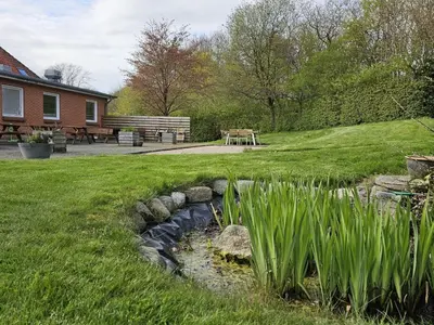 a stream in a yard with a bench and a table at Compact standard single room in Lemvig in Lemvig