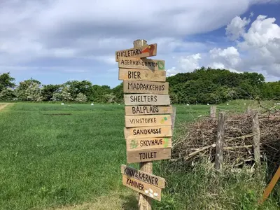a wooden sign with arrows in a field at 10 person holiday home in Spøttrup in Spottrup