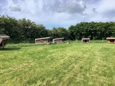 a large grass field with three buildings in the distance at 10 person holiday home in Spøttrup in Spottrup