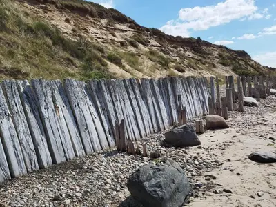 a wooden fence on the beach next to a hill at 10 person holiday home in Spøttrup in Spottrup