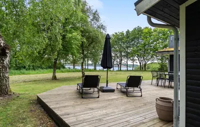 a wooden deck with two chairs and an umbrella at Amazing Home In Roslev With Wifi in Roslev
