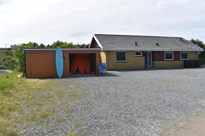 a house with a garage with a surfboard next to it at Viking Surf Home in Klitmøller